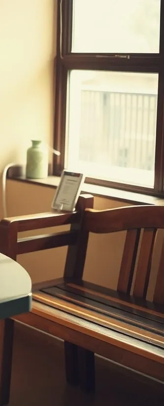 A wooden bench by a sunny window in a small waiting room